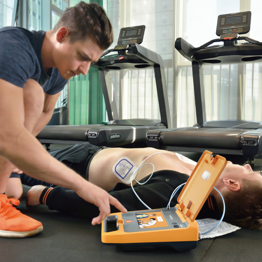First responder using Mindray BeneHeart C1A automated external defibrillator on patient in gym setting